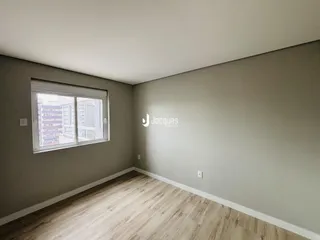 Sala de estar com piso de madeira clara e parede cinza.