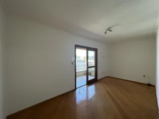Ambiente interno com piso de madeira e porta de vidro abrindo para o exterior.