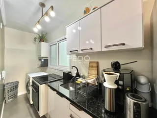 Cozinha moderna com armários brancos e bancada escura.