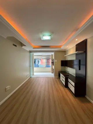 Corredor interno com piso de madeira e iluminação embutida.