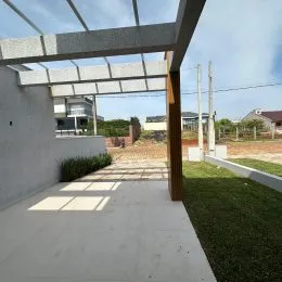 Área externa coberta com piso de concreto e vegetação.