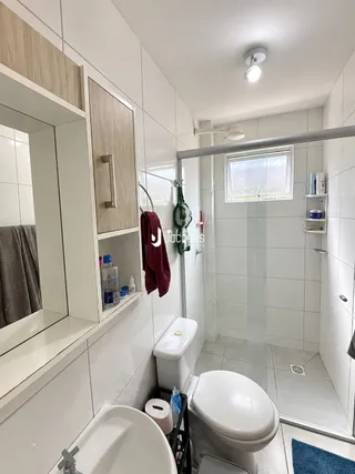 Interior de um banheiro com revestimento cerâmico branco.