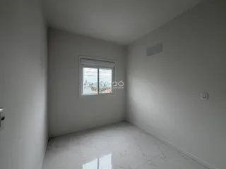 Vista interna de um cômodo com piso de mármore claro e paredes brancas.