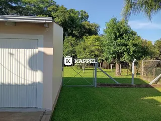 Vista externa da propriedade com gramado e portão de metal.
