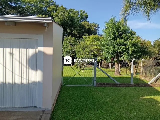 Vista externa da propriedade com gramado e portão de metal.