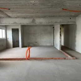 Foto de um espaço interno em estado bruto com piso de concreto.