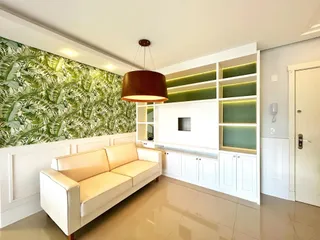 Sala de estar com parede verde e móveis brancos em um imóvel no Brasil.