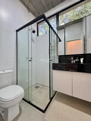 Banheiro com box de vidro e revestimento de mármore escuro.