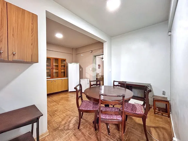 Ambiente interno com mesa de jantar de madeira e vista para outra sala.