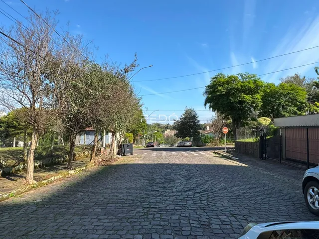 Vista da entrada de uma propriedade com paisagismo e pavimento de paralelepípedos.