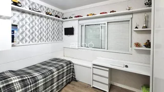 A foto mostra o interior de um quarto com cama e estantes brancas.