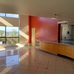Ambiente interno com parede vermelha e piso claro, apresentando um balcão de madeira.