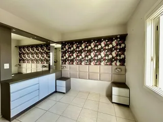 Quarto com cabeceira estofada e armários embutidos em um imóvel.