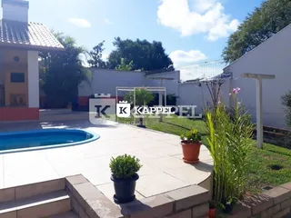 Vista externa de uma piscina com deck e jardim em uma propriedade em Lajeado.