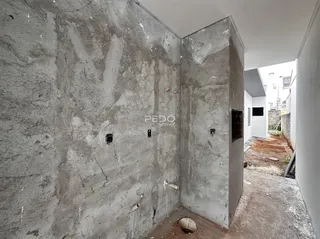 Parede de concreto aparente em um canto de imóvel com logotipo da imobiliária.