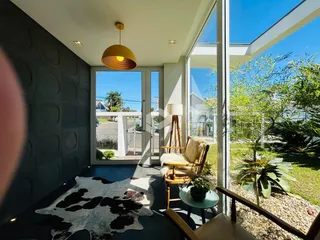 Uma sala de estar com grandes portas de vidro que oferecem vista para o jardim externo.