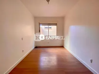 Foto de um corredor interno com piso de madeira polida.