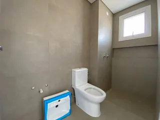 Uma foto do interior de um banheiro com vaso sanitário branco e bancada.