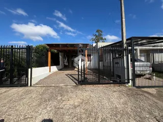 Fachada da residência em Lajeado, Brasil, com portão de ferro e entrada coberta.
