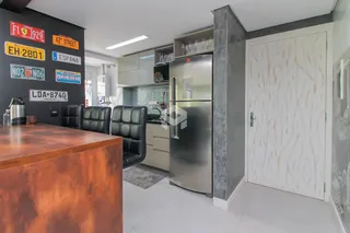 Interior de uma sala de jantar com móveis de couro e cozinha moderna.