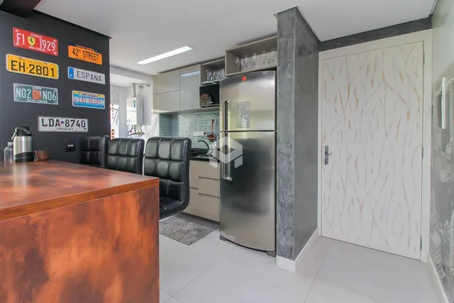 Interior de uma sala de jantar com móveis de couro e cozinha moderna.