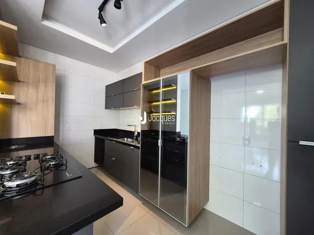 Imagem de uma cozinha moderna com armários e bancadas escuras.