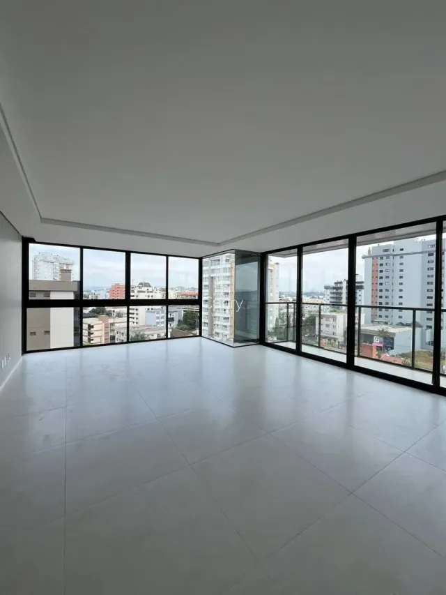 Sala ampla com grandes janelas que oferecem vista da cidade.
