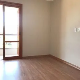 Ambiente interno com piso de madeira e grande janela iluminada.