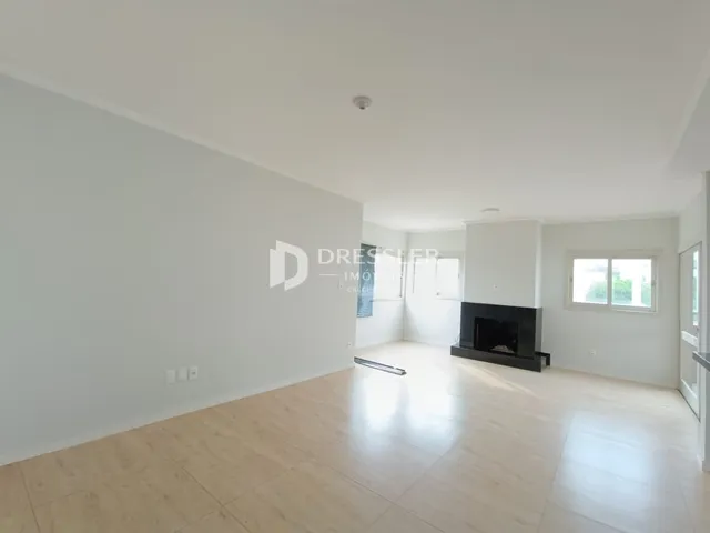 Ambiente interno de uma sala com piso de madeira clara e lareira.