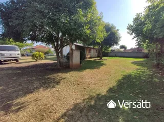 Vista externa de um terreno com grama seca e árvores no fundo.