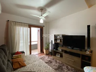 Quarto com sofá e televisão em ambiente claro.