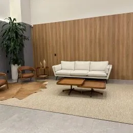 Sala de estar com sofá claro e painel de madeira na parede.