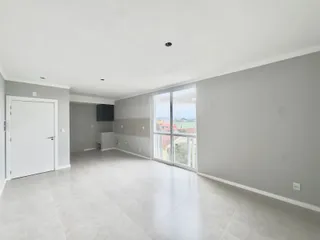 Ambiente interno amplo com piso claro e grandes janelas que oferecem vista.