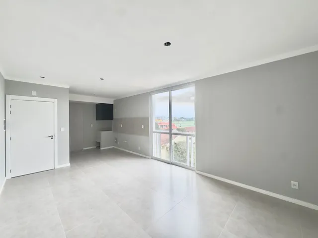 Ambiente interno amplo com piso claro e grandes janelas que oferecem vista.