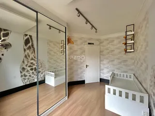 Quarto com piso de madeira e armário branco em um imóvel no Brasil.