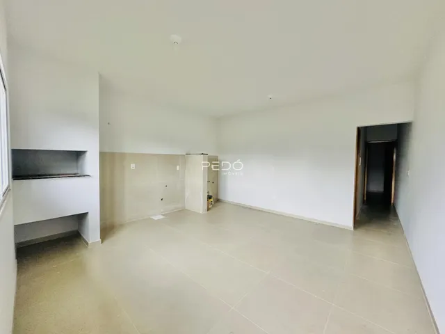 Ambiente interno de uma sala ampla com piso claro e paredes brancas.