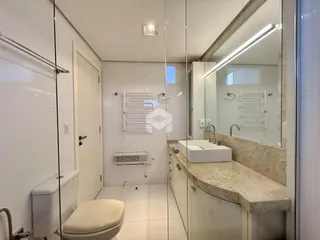 Foto interna de um banheiro com revestimento cerâmico e bancada de granito.