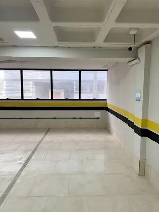 Vista interna de um corredor com piso de cerâmica e grande janela.