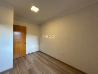 Hall de entrada com piso de madeira clara e paredes brancas.