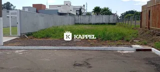 Foto da fachada de uma propriedade mostrando um muro de concreto e área externa com vegetação.