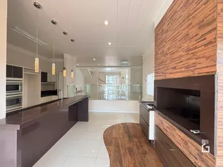 Ambiente moderno de cozinha e sala de jantar com piso claro e detalhes em madeira.