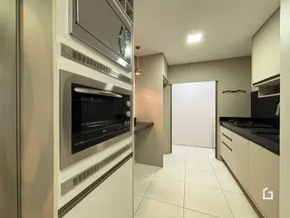 Vista interna de uma cozinha moderna com revestimento de cerâmica clara.