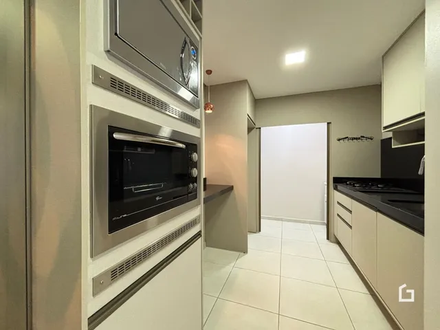Vista interna de uma cozinha moderna com revestimento de cerâmica clara.