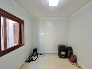 Interior de uma sala com parede branca e piso de cerâmica.