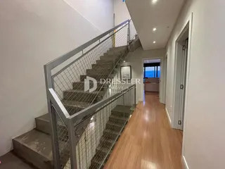 Hall de entrada com escadaria e piso de madeira em um imóvel.