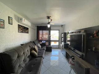 Sala de estar com sofá e televisão em um apartamento no Brasil.