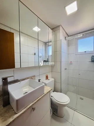 Banheiro com box de vidro e bancada de granito claro.