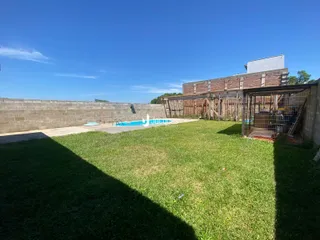 Vista externa de uma propriedade com gramado e piscina.