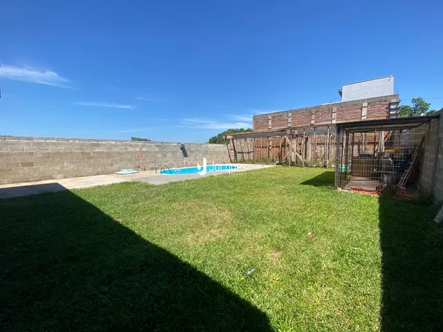 Vista externa de uma propriedade com gramado e piscina.