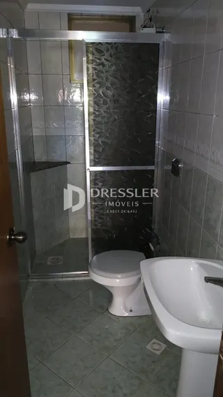 Foto de um banheiro com revestimento cerâmico e box de vidro.